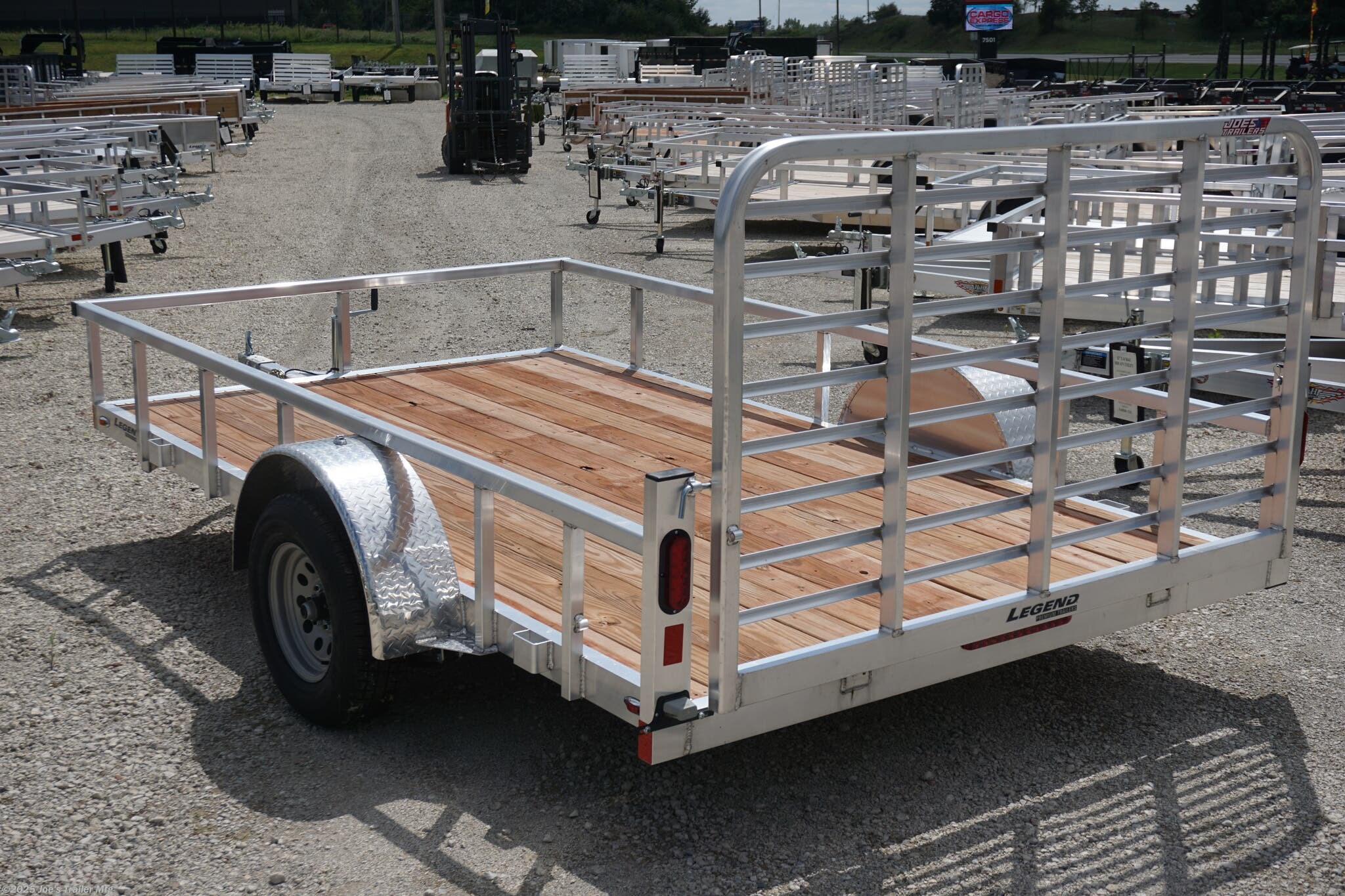 Legend 7x12 Open Deluxe Utility Trailer, 17" deck height utility trailer, 48" ramp gate trailer, 3.5k EZ-Lube spring axle, ST205/75R14 Silver Mod steel tires, 3" tube cross members, 24" on center cross member spacing, 4" tube frame trailer, aluminum flooring utility trailer, LED lighting trailer, 2" straight coupler, 2k top-wind jack, ATP fenders, stake pockets, aluminum utility trailer, open deluxe trailer, Legend utility trailer, lightweight utility trailer, durable trailer frame, trailer with LED lights, easy-to-lube axle, high-quality utility trailer, trailer with ramp gate, spring axle utility trailer, Legend trailer features, utility trailer with aluminum flooring, adjustable coupler trailer, top-wind jack utility trailer, trailer with ATP fenders, customizable utility trailer, Legend open trailer, utility trailer for heavy loads, trailer for equipment transport, low-profile utility trailer, trailer with stake pockets, utility trailer for landscaping, 12' utility trailer, trailer