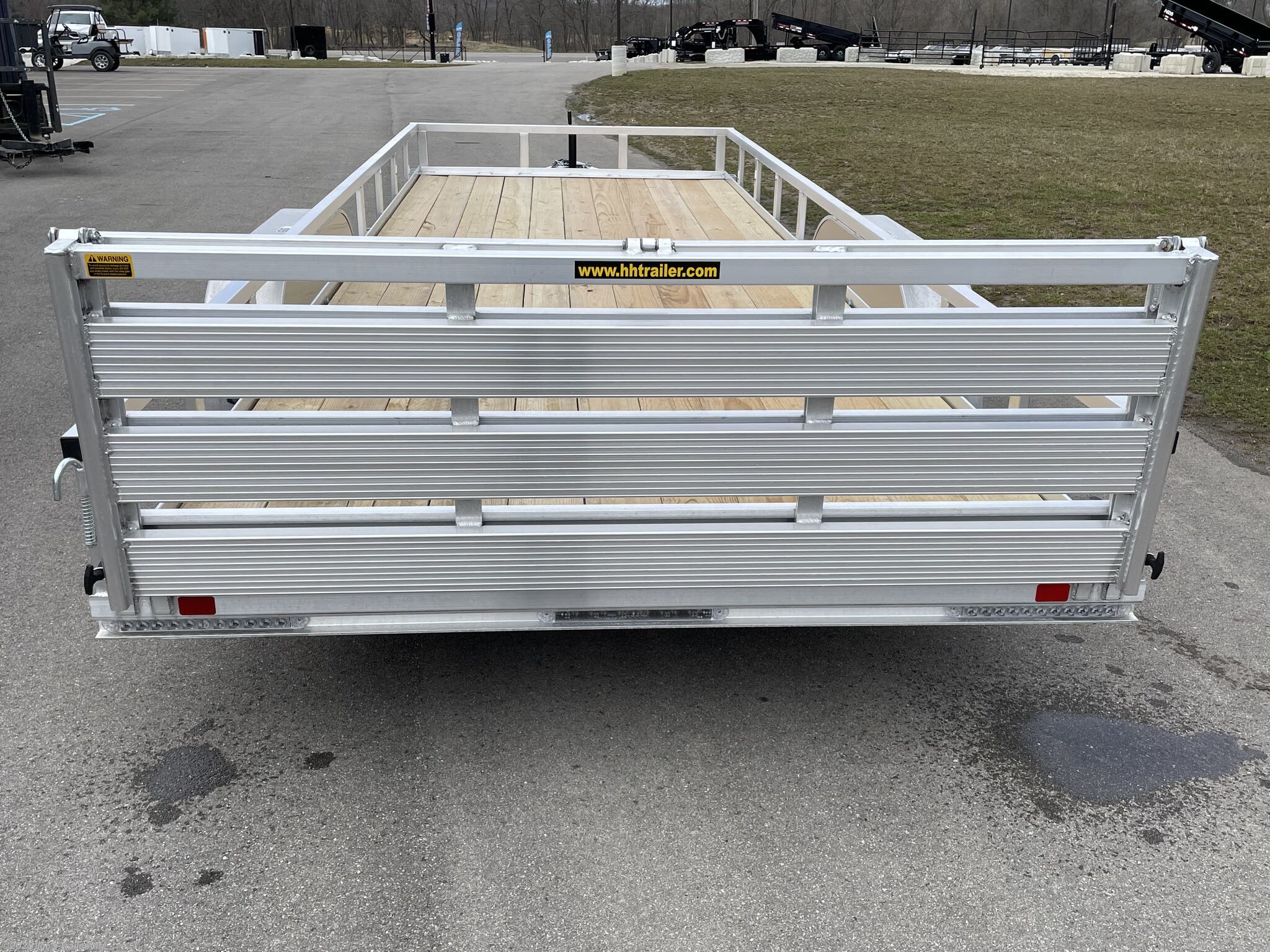 Aluminum Rail Side Tandem Utility Trailer H8218TRSA H&H Aluminum Rail Side Utility, aluminum angle extrusion frame, 3" x 2" aluminum frame, 3" aluminum channel crossmembers, tandem axle trailer, 5" aluminum triple tube tongue, 2" x 1-1/2" aluminum uprights, 2" x 2" aluminum top rail, 2-5/16" A-Frame posi-lock coupler, dual safety chains and hooks, 7-way RV-style plug, sealed wiring harness, 2k rated setback jack, 54" aluminum bi-fold gate, aluminum teardrop fenders, tandem spring brake suspension, 7000 lb GVWR, easy lube hubs, ST205/75R15 C tires, 15" aluminum wheels, 2 x 8 pressure treated pine decking, front and rear end board caps, aluminum stake pockets, full LED DOT compliant lighting, load angle and ramp length, 17° load angle, 58" ramp length, ramp pivot point, aluminum utility trailer, H&H utility trailer, aluminum rail side trailer, aluminum trailer with stake pockets, tandem axle utility trailer, aluminum deck trailer, aluminum fender trailer, DOT compliant utility trailer, a