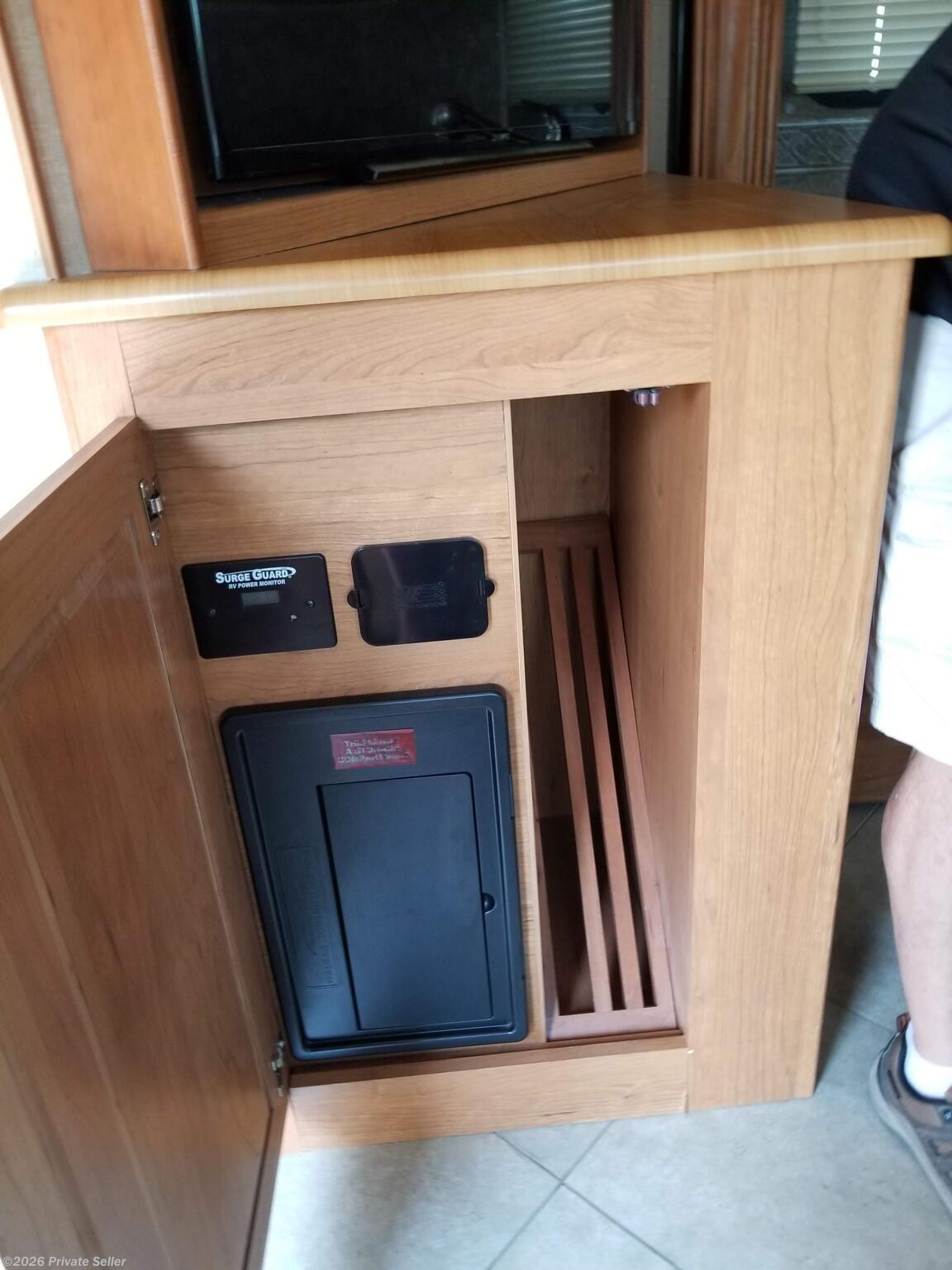 Left of sink, below TV, elec fuse panel and storage for solid sink covers and cooktop cover